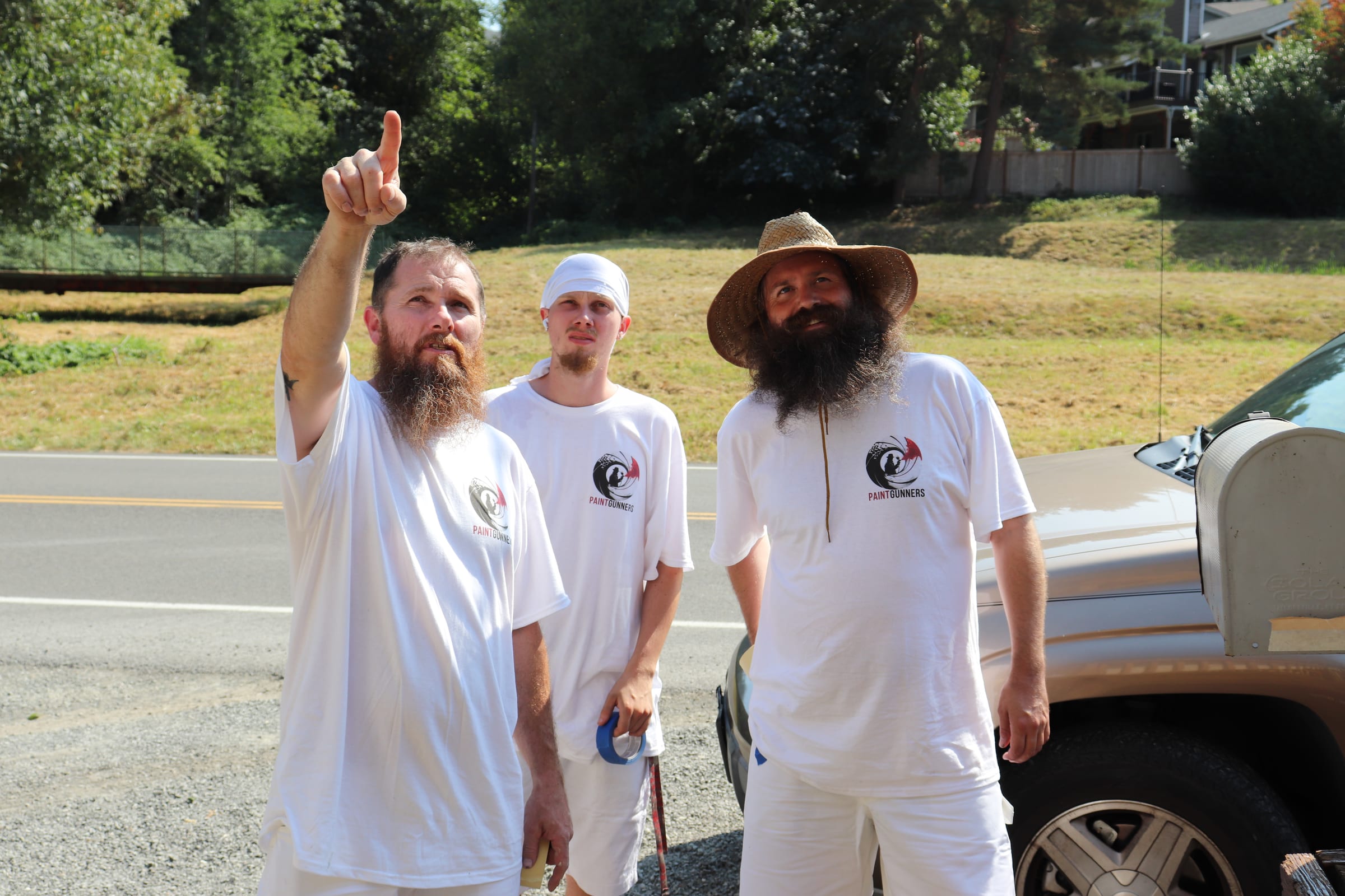 Three Paint Gunners crew members standing together beside their truck at a job site