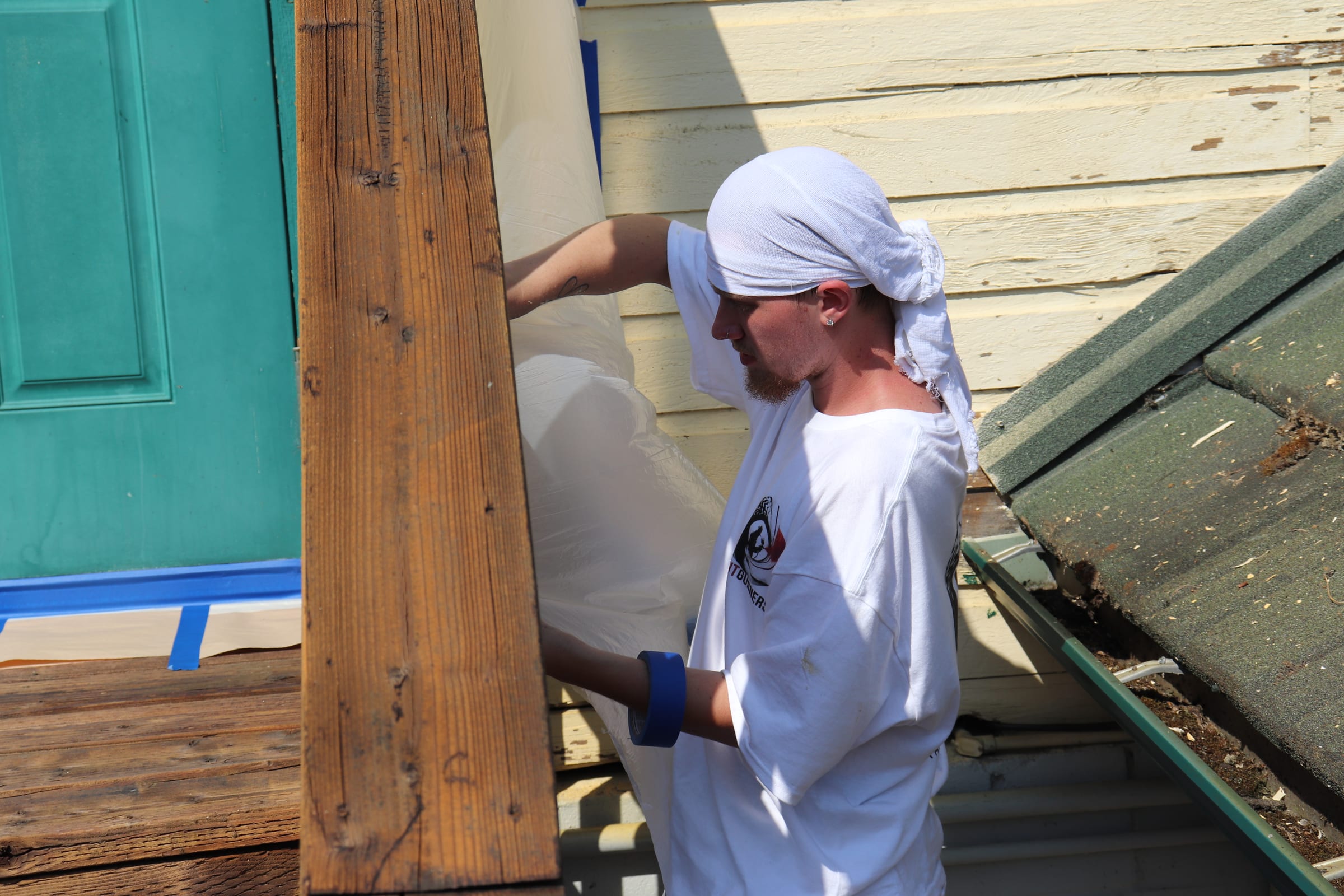 Painter pulling masking film into place beside a door on an exterior wall