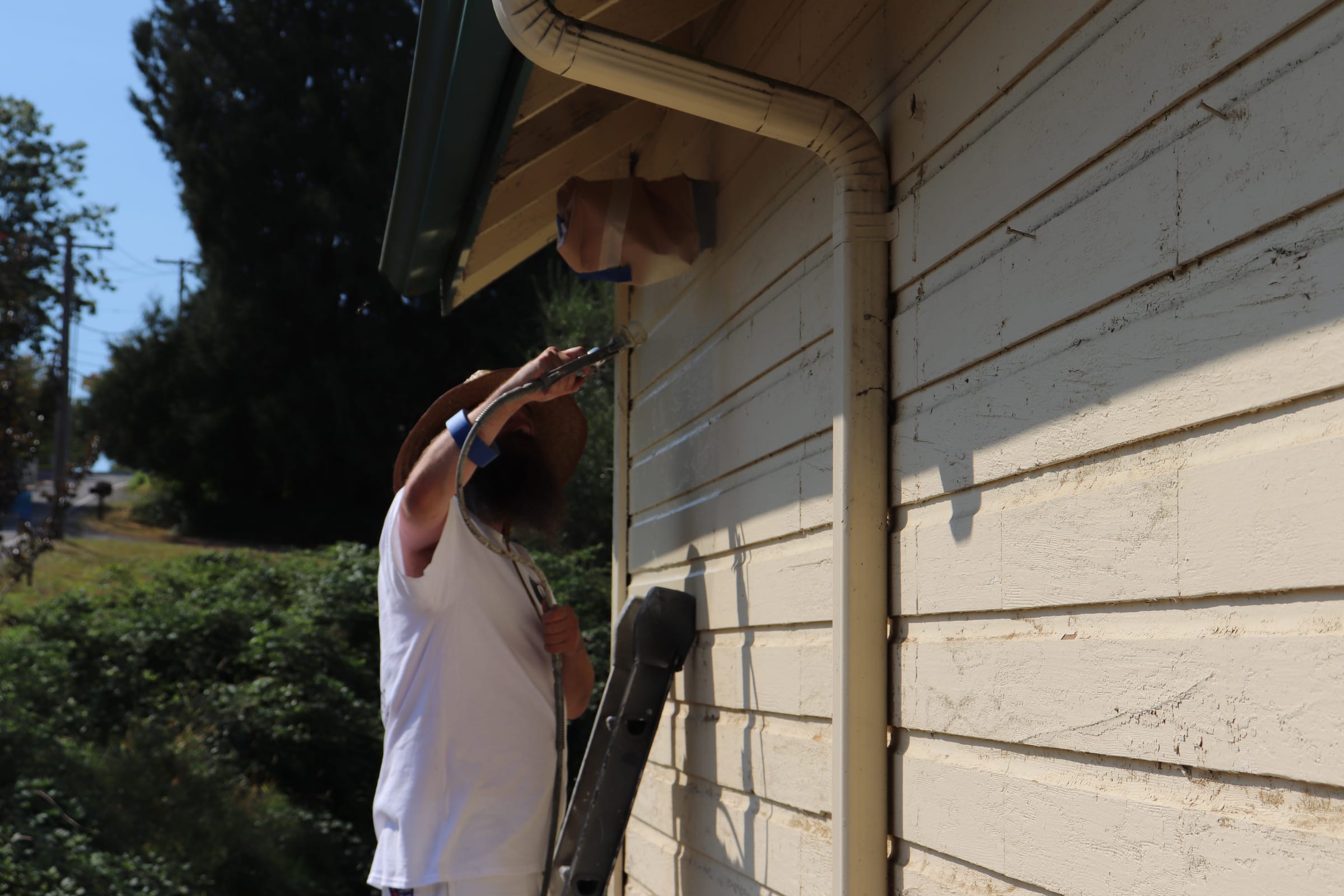 Painter working overhead into the eave of an exterior wall