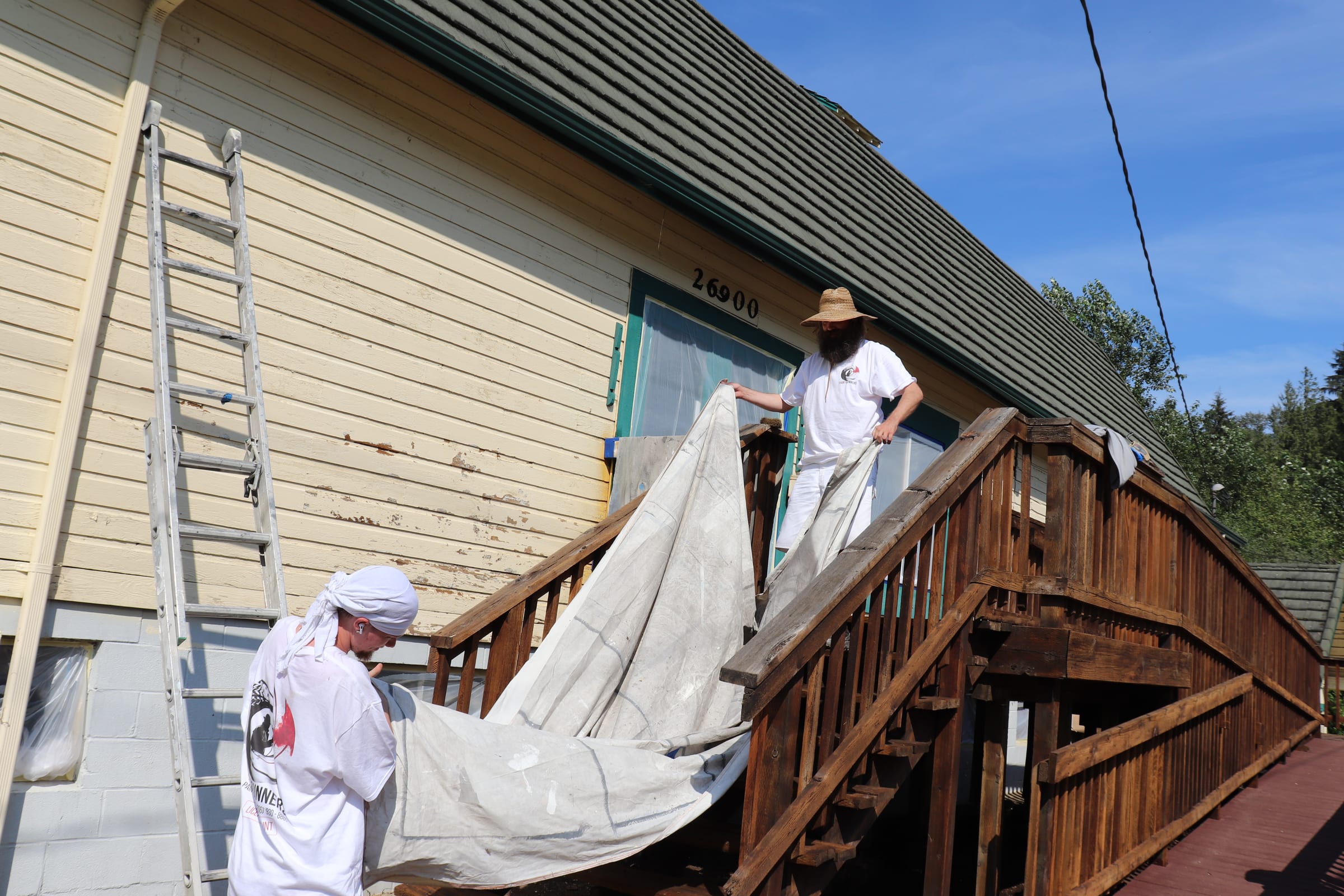 Two painters carrying a canvas drop cloth up an exterior staircase