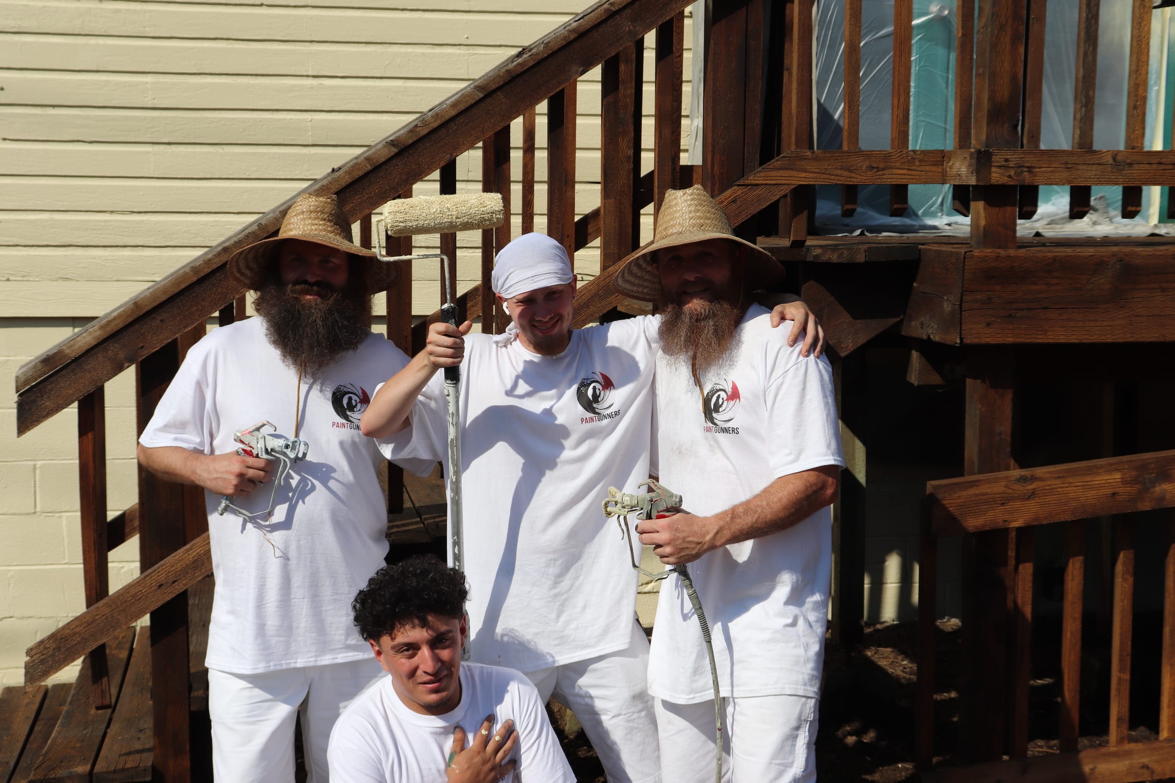 Four Paint Gunners crew members gathered on an exterior staircase at a job site